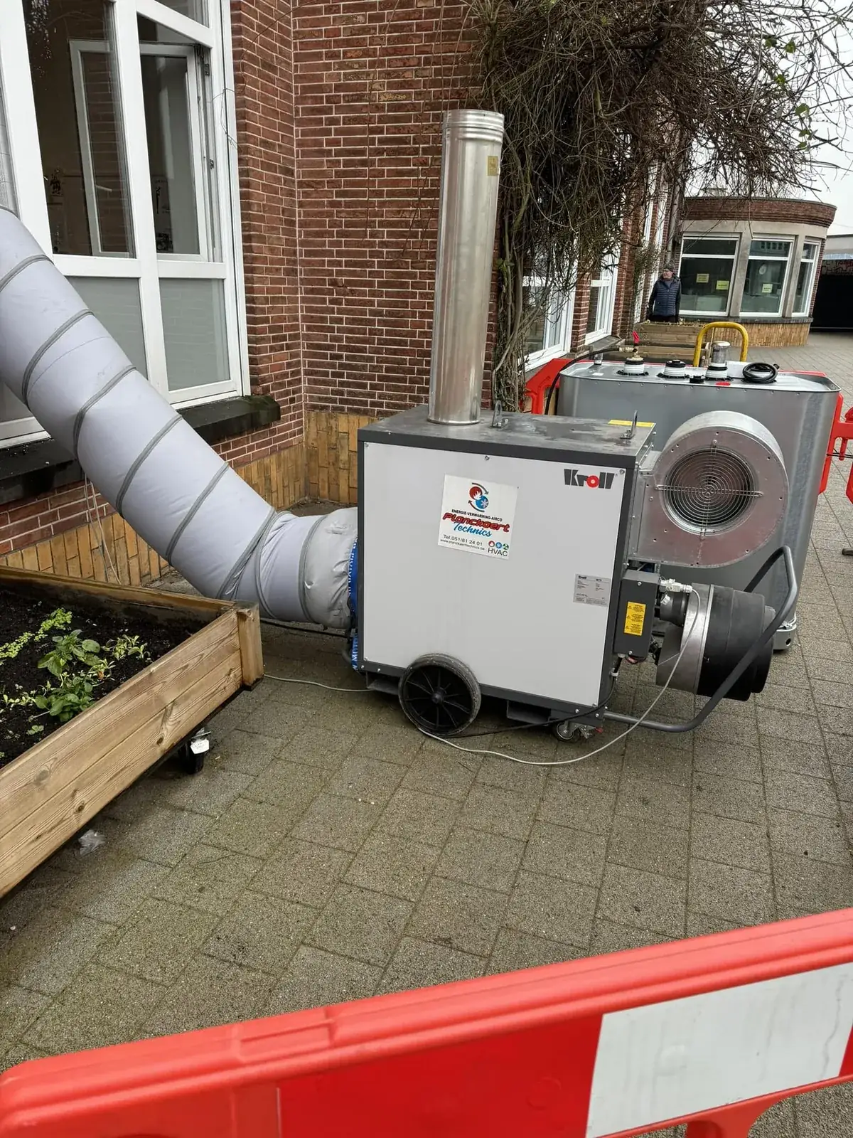 Mobiele brander met luchtslang aan een gevel in bedrijf